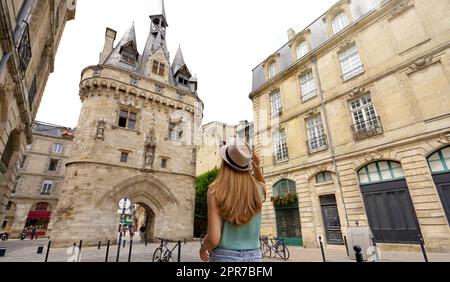 Tourismus in Bordeaux, Frankreich. Reisendes Mädchen, das in Bordeaux unterwegs ist und Porte Cailhau, ein mittelalterliches Torhaus der alten Stadtmauer, entdeckt. Stockfoto