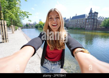 Selfie einer jungen Frau mit dem Gebäudekomplex Binnenhof auf Hofvijver in Den Haag, Niederlande Stockfoto