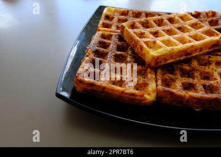 Zum Servieren werden süße Waffeln zubereitet. Ein leckeres Dessert mit Obst und Konserven gegessen. Dunkler Hintergrund. Stockfoto