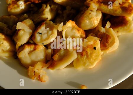Hausgemachte Kartoffelknödel oder Vereniki-Pierogi, serviert mit gebratenen Zwiebeln. Rustikaler Stil, komfortable osteuropäische Küche Stockfoto