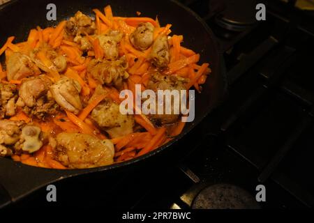 Hausgemachtes koreanisches würziges Hühnchen, Chiken mit Karotten in einer Pfanne mit Sonnenblumenöl braten. Stockfoto