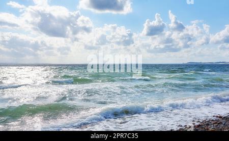 Küste von Kattegat - Helgenaes, Dänemark. Ozeanwellen, die sich auf das leere Strandufer spülen. Ruhiges, friedliches Paradies der Sommerlandschaft und des Himmels für einen erholsamen Urlaub im Ausland oder einen Urlaub im Ausland Stockfoto