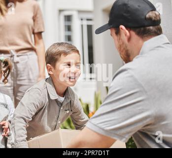 Ich bin der Mann des Hauses. Kurzer Schuss eines entzückenden kleinen Jungen, der die Lieferung seiner Mutter von einem männlichen Kurier abholte. Stockfoto