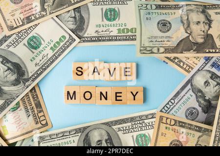 Geld in internationaler Währung, Dollars liegen auf blauem Hintergrund. Die Inschrift spart Geld. Stockfoto