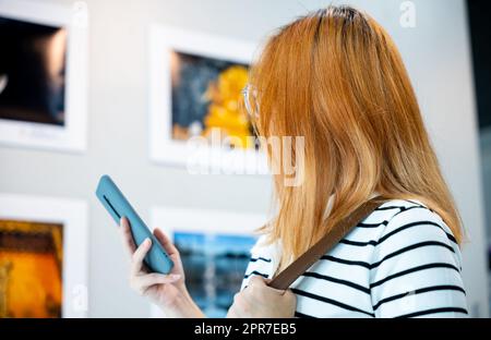 Die stehende Besucherfrau macht eine Sammlung von Kunstgalerien auf Bildern mit Vorderrahmen Stockfoto