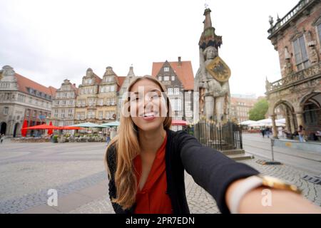 Schöne Frau macht Selbstporträt auf dem Bremer Marktplatz mit Roland-Statue, Bremen, Deutschland Stockfoto