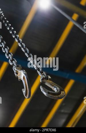 Metallhaken, der an einer Kette hängt, in einer Fabrik, die sich auf den Haken konzentriert Stockfoto