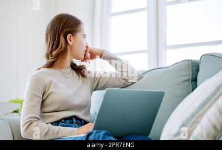 Shes hat sich viel in den Kopf gesetzt. Kurze Aufnahme einer attraktiven jungen Frau, die nachdenklich aussieht und sich zu Hause auf dem Sofa entspannt. Stockfoto