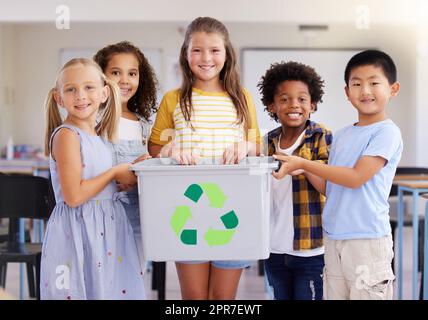 Kleine Kinder sind von Natur aus neugierig und aufmerksam. Aufnahme einer Gruppe von Vorschulkinder, die einen Recyclingbehälter in der Klasse halten. Stockfoto