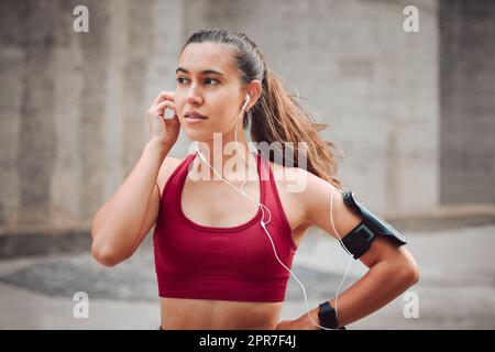 Nur die Motivation, die sie brauchte. Kurze Aufnahme einer attraktiven jungen Sportlerin, die beim Laufen im Freien Musik hört. Stockfoto