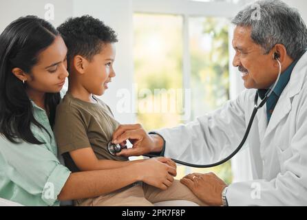 Du bist ein gesunder Junge. Aufnahme eines reifen Arztes, der einen kleinen Jungen zu Hause untersucht. Stockfoto