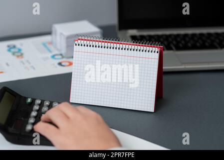 Leeres geöffnetes Spiralnotizbuch mit einem Taschenrechner und einem Stift über Einem Tisch. Leerer linierter Notizblock und Bleistift auf Einem Schreibtisch mit einem Taschenrechner. Stockfoto