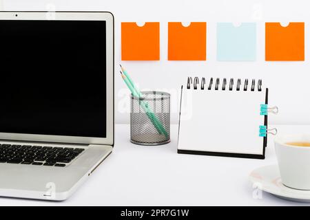 Wichtige Mitteilungen Auf Dem Notebook Und Laptop Auf Dem Schreibtisch Mit Notizen, Bleistiften Und Einer Tasse Tee. Grundlegende Informationen Auf Dem Computerbildschirm Und Notizblock Auf Dem Tisch Mit Bürobedarf. Stockfoto