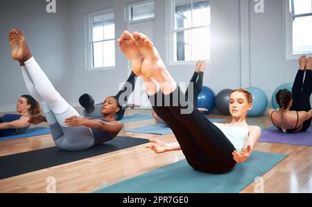 Nur noch ein paar Sekunden. Aufnahme einer Gruppe von Studenten, die während eines Pilates-Kurses Crunches durchführen. Stockfoto