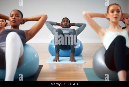 Das können wir gemeinsam tun. Aufnahme einer Gruppe von Studenten, die während eines Pilates-Kurses Crunches durchführen. Stockfoto