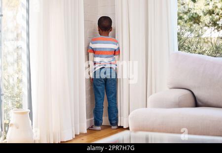 Zeit, darüber nachzudenken, was du getan hast. Ein kleiner Junge, der zu Hause als Strafe in der Ecke steht. Stockfoto