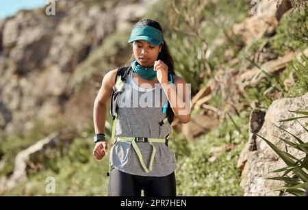 Jeder Trail wird Sie herausfordern. Eine junge Frau, die auf einem Trail auf dem Berg läuft. Stockfoto