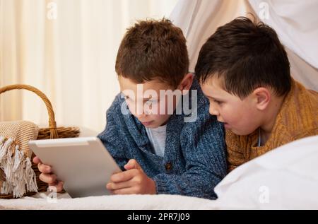 Zwei Brüder, die ein digitales Tablet zusammen unter einer Decke Fort zu Hause verwenden. Stockfoto