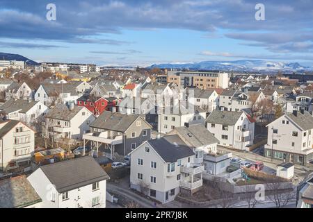 Die kleine Stadt Bodo in Norwegen mit einem bewölkten oder bedeckten blauen Himmel. Ein schöner malerischer Blick auf die Straßen und Gebäude der Stadt mit Kopierbereich. Friedliche ländliche Stadt von oben Stockfoto