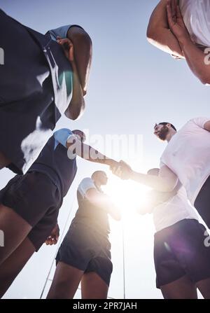 Unter zwei gegnerischen Rugby-Teams, die vor oder nach einem Spiel draußen auf einem Feld die Hand schütteln. Rugby-Spieler teilen sich den Handschlag, um Respekt und Sportlichkeit zu zeigen. Ein gegenseitiges Verständnis des Spiels Stockfoto