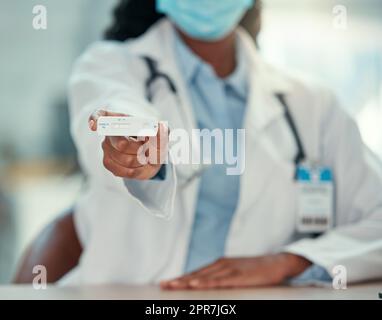 afroamerikanischer Arzt mit negativem Covid-Test. Hand eines Arztes, der einen Corona-Virus-Test hält. Arzt trägt eine Maske, um sich vor der Covid-Krankheit zu schützen. Stockfoto