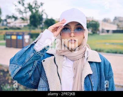 Wunderschöne junge araberin, die sich draußen in einem Kopftuch posiert. Attraktive moslem trägt einen Hijab und posiert draußen. Sie steht für Stil und Mode. Gemischte Rasse, die selbstbewusst und trendig aussieht Stockfoto