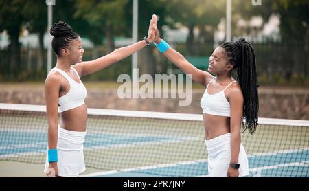 Glückliche Profi-Tennisspieler High Five nach einem Spiel auf dem Platz. Junge Mädchen unterstützen sich nach dem Tennistraining. Zwei Freunde, die sich nach dem Wettkampf im Tennisclub anfreunden Stockfoto