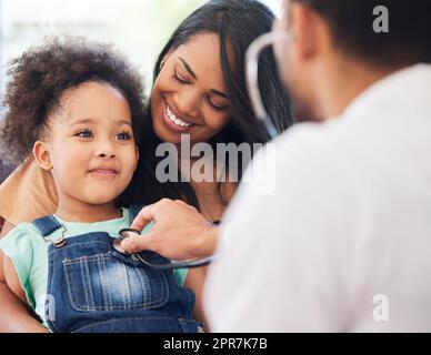 Ich bin jetzt ein großes Mädchen. Ein kleines Mädchen, das auf dem Schoß ihrer Mutter sitzt, während es von ihrem Arzt untersucht wird. Stockfoto