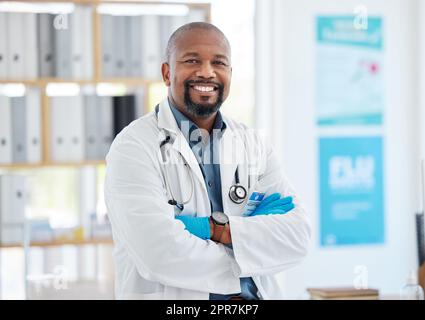 Stolzer, selbstbewusster junger Arzt in seiner Praxis. afroamerikanische Ärzte kreuzten in seinem Krankenhaus die Arme. Glücklicher Arzt in seinem Büro. Facharzt in seiner Klinik Stockfoto