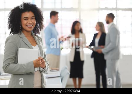 Junge, glückliche Geschäftsfrau aus gemischten Rassen, die in einem Büro steht. Eine selbstbewusste hispanische Chefin mit einem geschwungenen Afro-Lächeln und Stehen während eines Meetings bei der Arbeit Stockfoto