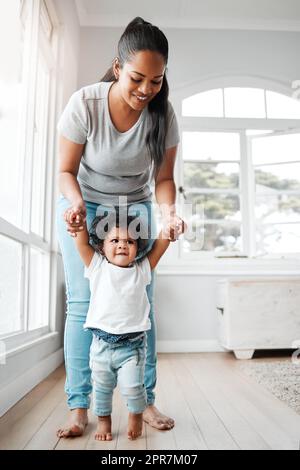 Ein kleines Mädchen, das mit Hilfe ihrer Mutter gehen lernt. Stockfoto