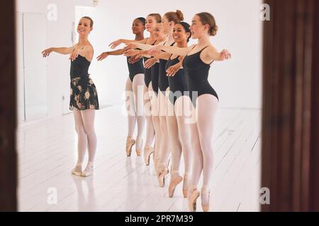 Eine junge Tanzlehrerin, die einer Gruppe von Kindern in ihrem Atelier einen Ballettunterricht gibt. Ballerina-Lehrerin, die mit Schülerinnen arbeitet, sich auf ihre Aufführung, ihre Vorstellung oder ihre bevorstehende Show vorbereitet Stockfoto