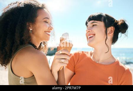 Es gibt keine bessere Jahreszeit für Spaß als der Sommer. Zwei attraktive junge Freundinnen genießen Eis am Strand. Stockfoto