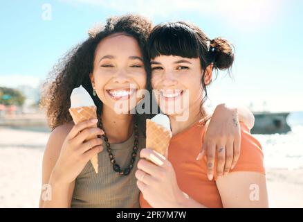 Eine weitere Saison der Freundschaft. Verkürztes Porträt zweier attraktiver junger Freundinnen, die am Strand Eis genießen. Stockfoto