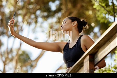 Eine attraktive junge Athletin, die Selfies beim Training im Freien macht. Stockfoto