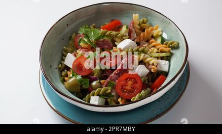 Italienische Nudelsalat Gurken, Kirschtomaten, Oliven, rote Zwiebeln, Salami, Feta-Käse und Rotini Stockfoto