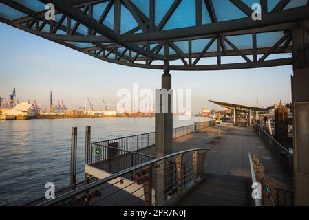 Der berühmte Anblick von Hamburg, der Landungsbrücken, an der elbe mit kleinen Booten. Leute, die durch einen Gang zum Pier laufen. Stockfoto