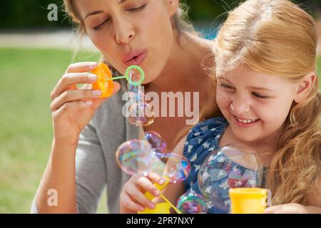 Lass dein inneres Kind raus. Aufnahme einer jungen Mutter, die mit ihrer Tochter Blasen bläst. Stockfoto