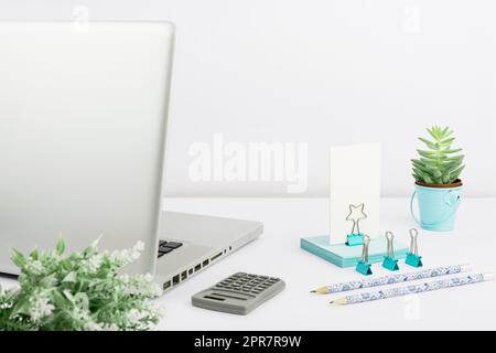 Laptop, Bleistifte, Taschenrechner, Büroklammern, Blumen Und Haftnotizen Auf Dem Schreibtisch. Computer, Stifte, Clips Und Memos Auf Dem Tisch. Bürobedarf Und Pc Am Arbeitsplatz. Stockfoto