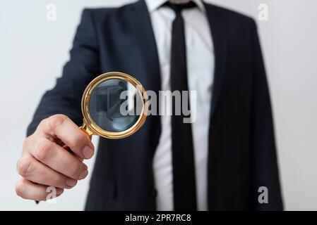 Geschäftsmann Mit Einer Lupe In Einer Hand. Ein Mann, Der Eine Lupe Hat, Um Auf Wichtige Informationen Hinzuweisen. Gentleman Zoomt Crutial Message. Führungskraft Präsentiert Neue Idee. Stockfoto