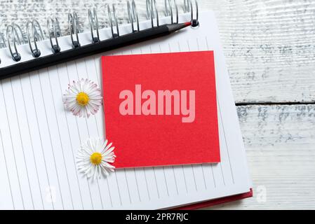 Haftnotiz Mit Wichtigen Mitteilungen Über Notizbuch Mit Bleistift Und Blumen Auf Dem Boden. Memo Mit Grausamen Informationen Über Notepad Am Boden Platziert. Stockfoto