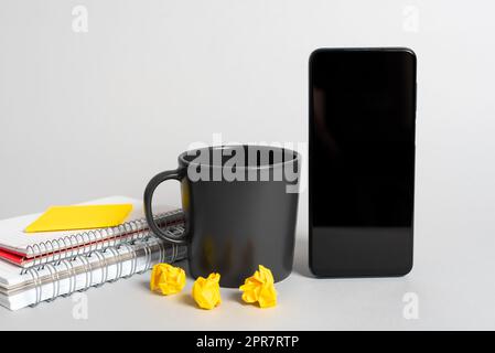 Becher, Notizbücher, Haftnotiz, Papierfolien Und Telefonbildschirm Mit Wichtiger Nachricht. Tasse, Zerknitterte Notizen Und Aktuelle Updates Auf Dem Tablet. Kaffee, Zerknitterte Memos Und Kritische Daten. Stockfoto