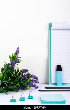 Blumen Auf Dem Schreibtisch Neben Der Zwischenablage Mit Wichtiger Nachricht, Büroklammern, Marker Und Notizen. Tasse Mit Stiften Auf Dem Tisch Mit Memos Mit Grausamkeiten Präsentiert. Stockfoto