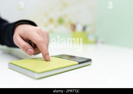 Geschäftsfrau Zeigt Auf Rechner Am Schreibtisch Mit Notizbuch. Frau Drückt Mit Notepad Auf Den Tisch. Führungskraft, Die Aktuelle Informationen Angezeigt Hat. Stockfoto