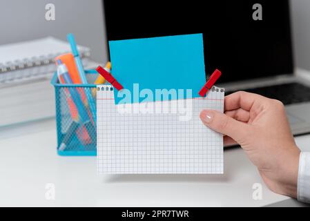 Geschäftsfrau, Die Notizen Mit Wichtigen Nachrichten Am Schreibtisch Mit Bleistiften Und Laptop In Der Hand Hält. Frau Im Anzug, Die Memos Mit Neuen Ideen In Der Hand Hat. Stockfoto