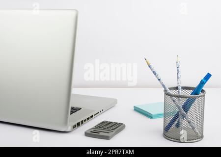 Laptop, Tasche Mit Bleistiften Und Markern, Taschenrechner Und Haftnotizen Auf Dem Schreibtisch. Computer, Farbstifte Und Memos Auf Dem Tisch. Bürobedarf Und Pc Am Arbeitsplatz. Stockfoto