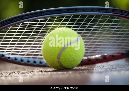 Tennisrakete über Tennisball mit Blick aus dem niedrigen Winkel Stockfoto