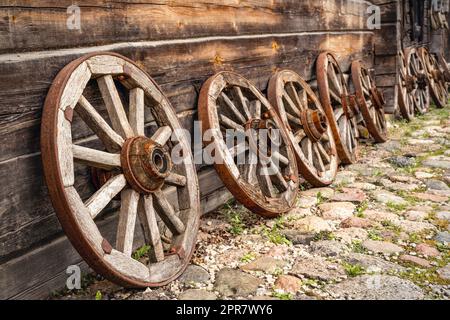 Alte Wagenräder aus Holz, die auf eine Blockhütte gelehnt sind Stockfoto