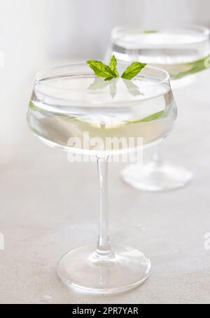 Transparenter Cocktail mit Eiswürfeln in einem Glas, das mit Minzblättern aus nächster Nähe verziert ist. Tropisches Getränk an der Bar. Sommerurlaubsstimmung. Analkolischer Mocktai Stockfoto