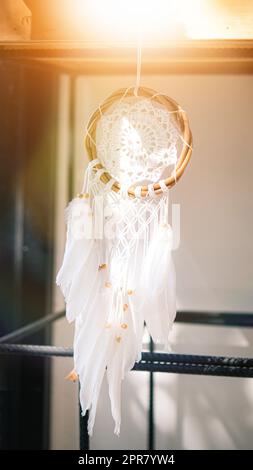 Weißer Traumfänger, der an einem Baum in Strahlen der Sonnenuntergangssonne hängt. stricken, handgefertigt, Hochzeit, Dekor Stockfoto